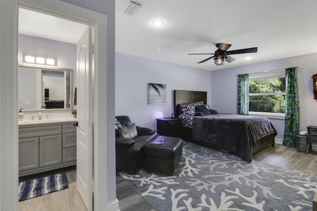 bedroom with ceiling fan, ensuite bath, sink, and light wood-type flooring