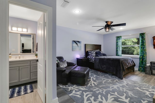 bedroom with ceiling fan, sink, ensuite bathroom, and light hardwood / wood-style flooring