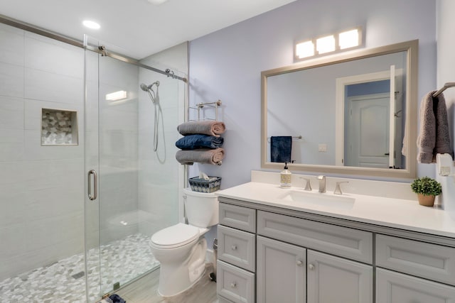 bathroom with hardwood / wood-style floors, vanity, toilet, and an enclosed shower