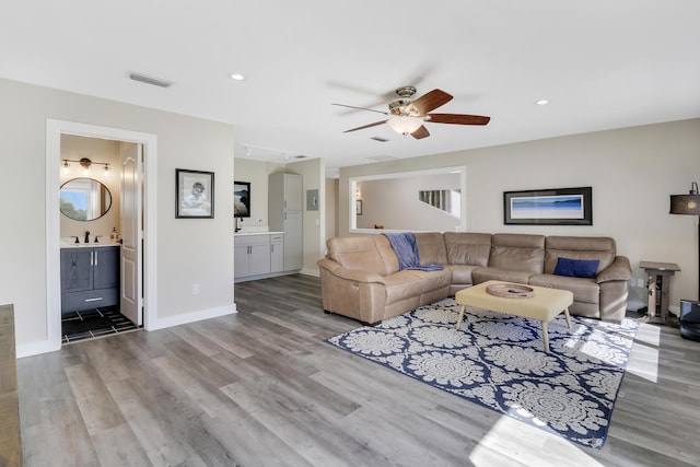 living room featuring rail lighting, sink, ceiling fan, and light hardwood / wood-style flooring