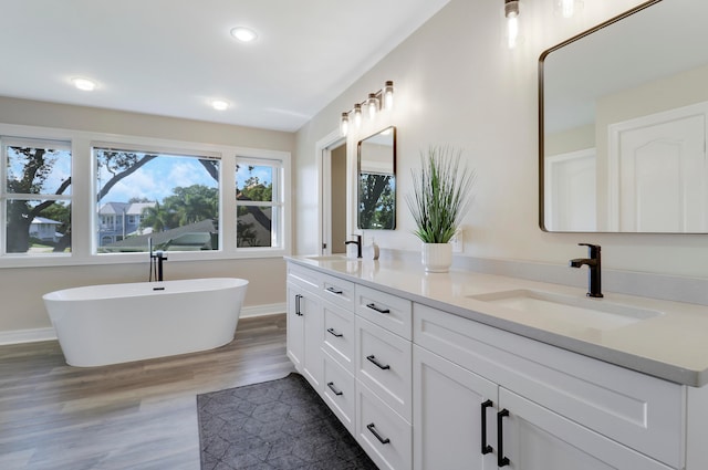 bathroom with a washtub, wood-type flooring, and vanity