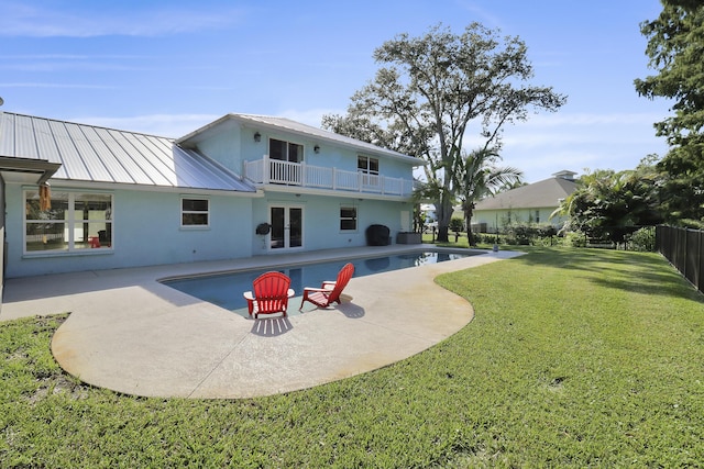 back of property featuring a fenced in pool, a patio area, a balcony, and a lawn