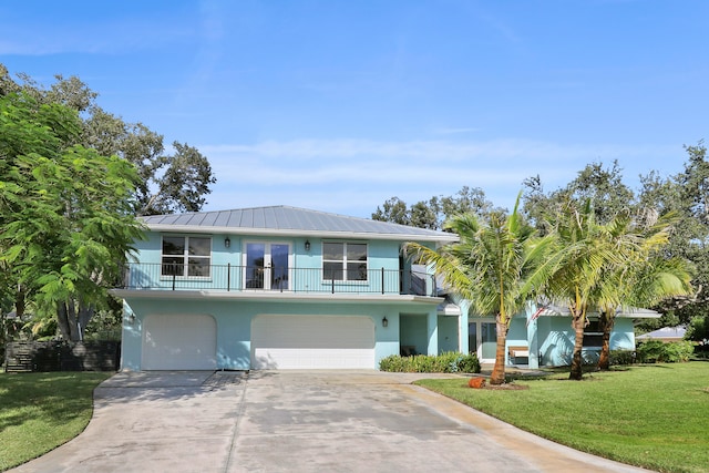 beach home featuring a balcony, a garage, and a front lawn