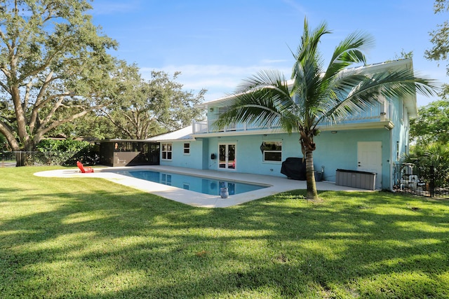 rear view of house featuring a lawn, a patio area, and a fenced in pool