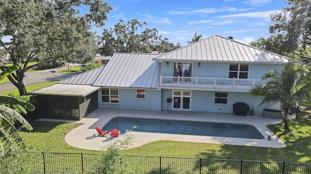 rear view of property with a balcony, a yard, a fenced in pool, and a patio