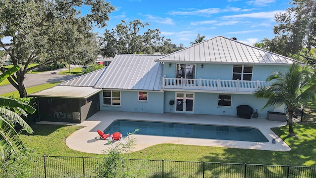 back of house with a balcony, a patio area, a sunroom, a yard, and a fenced in pool