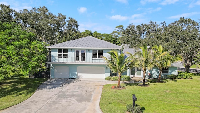 raised beach house with a front yard, a balcony, and a garage