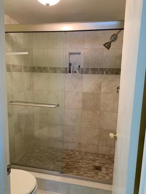 bathroom featuring toilet and a shower with shower door