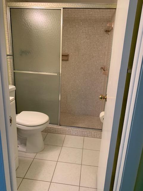 bathroom featuring tile patterned flooring, walk in shower, and toilet