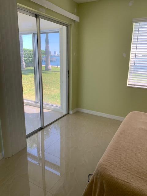 2936 Lake Shore Dr Unit 101, Riviera Beach, FL 33404 - bedroom with access to exterior, light tile patterned floors, and baseboards