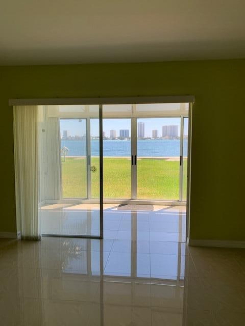 spare room with a water view, light tile patterned floors, and plenty of natural light