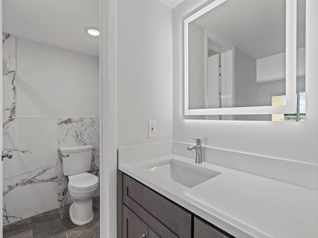 bathroom featuring tile walls, vanity, and toilet