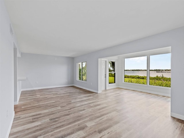 spare room featuring light hardwood / wood-style floors, a water view, and a wealth of natural light