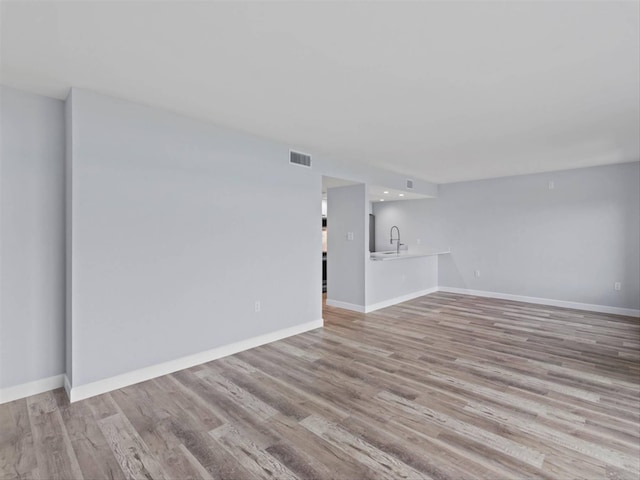 unfurnished living room featuring light hardwood / wood-style flooring and sink