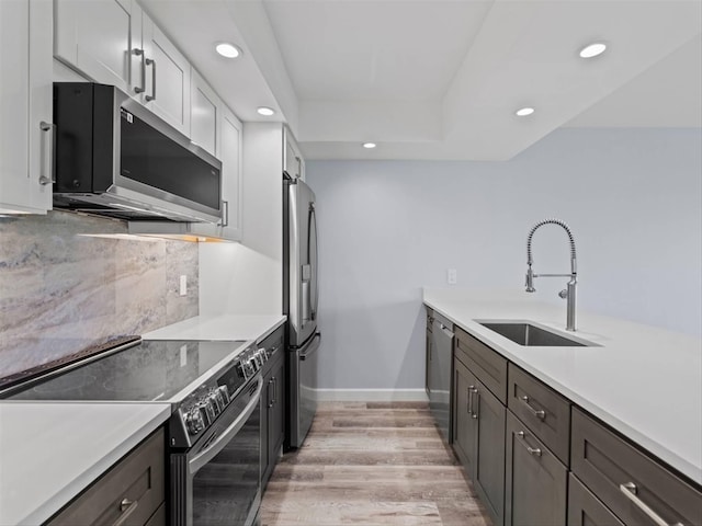 kitchen with light wood-type flooring, white cabinetry, sink, and stainless steel appliances