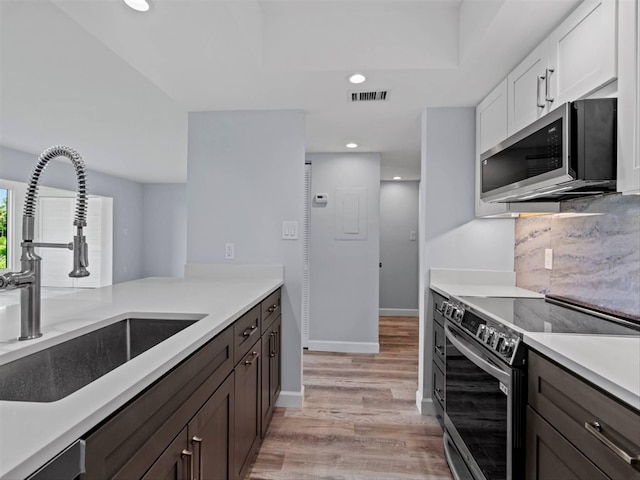 kitchen featuring light hardwood / wood-style floors, white cabinetry, stainless steel appliances, dark brown cabinetry, and sink