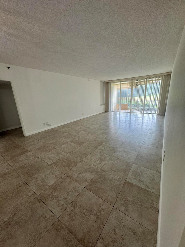 empty room featuring a textured ceiling and a wall of windows