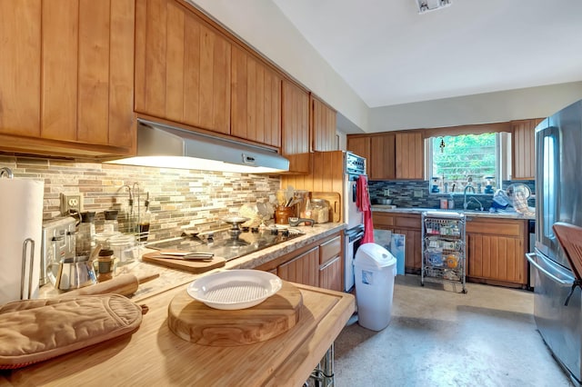 kitchen featuring decorative backsplash, stainless steel refrigerator, fridge, black electric stovetop, and extractor fan