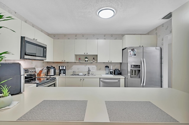 kitchen featuring stainless steel appliances, white cabinetry, a textured ceiling, and sink