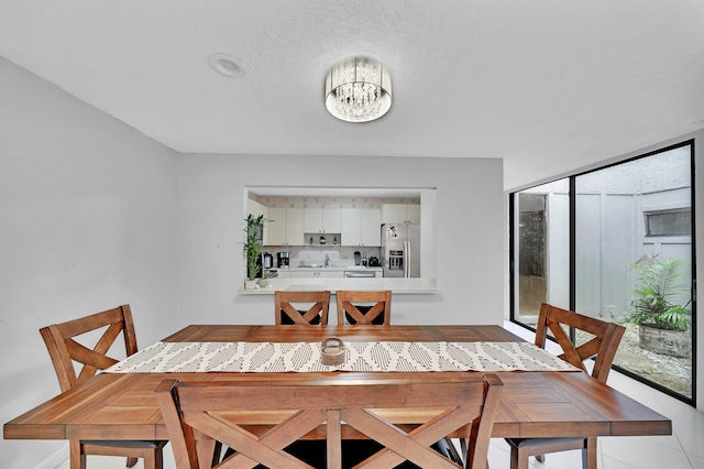 tiled dining space with a textured ceiling and a chandelier