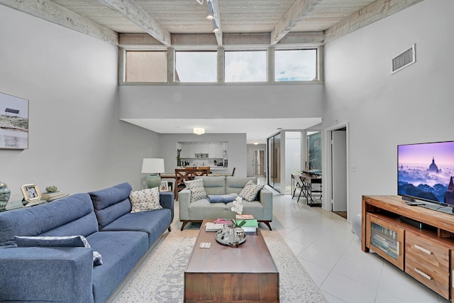 tiled living room with wooden ceiling, rail lighting, beam ceiling, and a towering ceiling