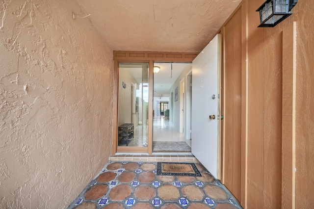 corridor featuring a textured ceiling and tile patterned flooring