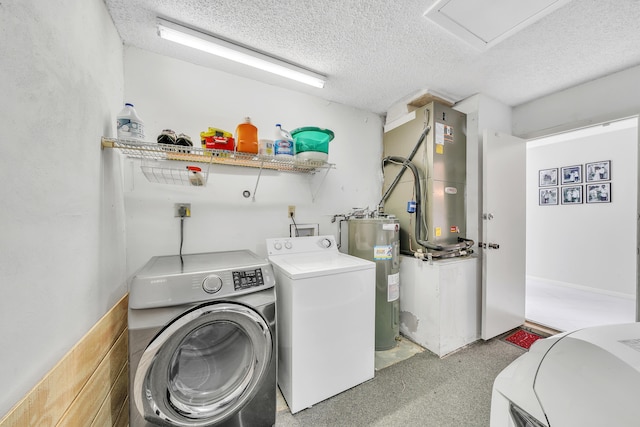 laundry room with a textured ceiling, water heater, washing machine and clothes dryer, and heating unit