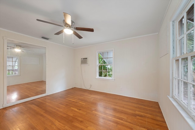 empty room with a wall unit AC, crown molding, hardwood / wood-style floors, and ceiling fan