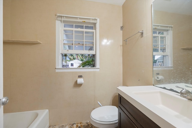 bathroom with vanity, toilet, a bathtub, and a healthy amount of sunlight