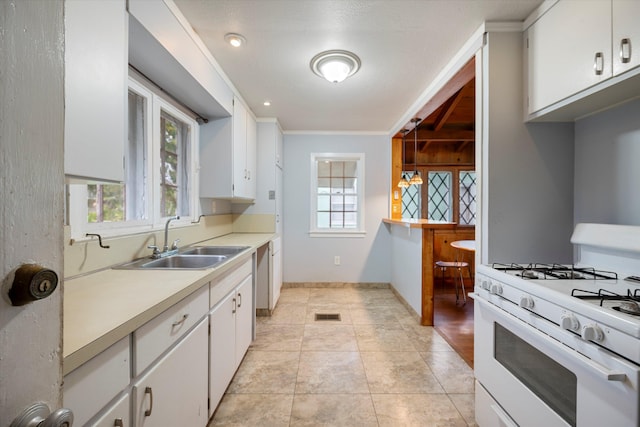 kitchen featuring sink, hanging light fixtures, ornamental molding, white gas stove, and white cabinetry