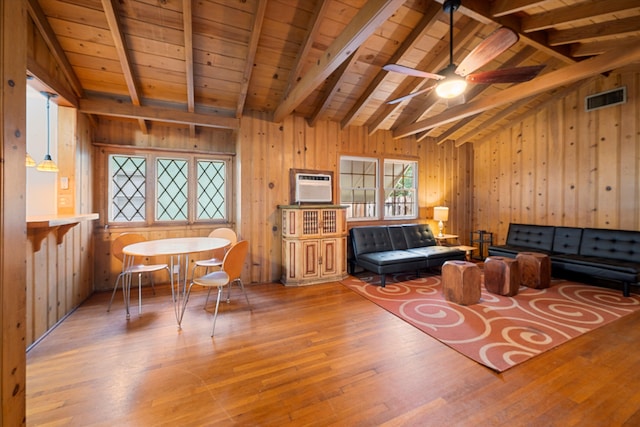 living room with lofted ceiling with beams, wooden walls, and wood-type flooring