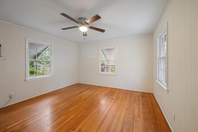 empty room with crown molding, ceiling fan, a healthy amount of sunlight, and wood-type flooring