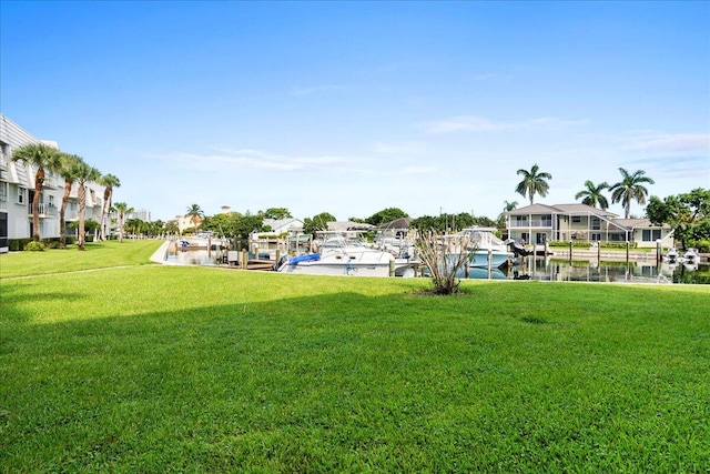 view of home's community with a lawn, a water view, and a dock