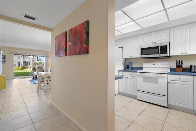 kitchen with white appliances, white cabinetry, and light tile patterned flooring