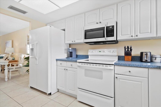 kitchen with white appliances, white cabinetry, and light tile patterned flooring