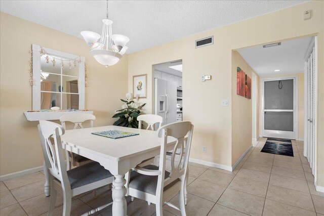 tiled dining room featuring a textured ceiling and a notable chandelier