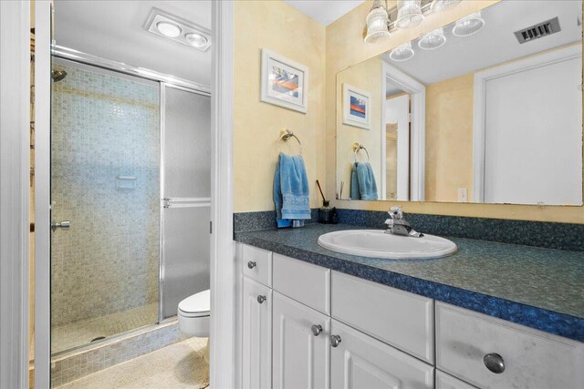 bathroom featuring a shower with shower door, vanity, and toilet