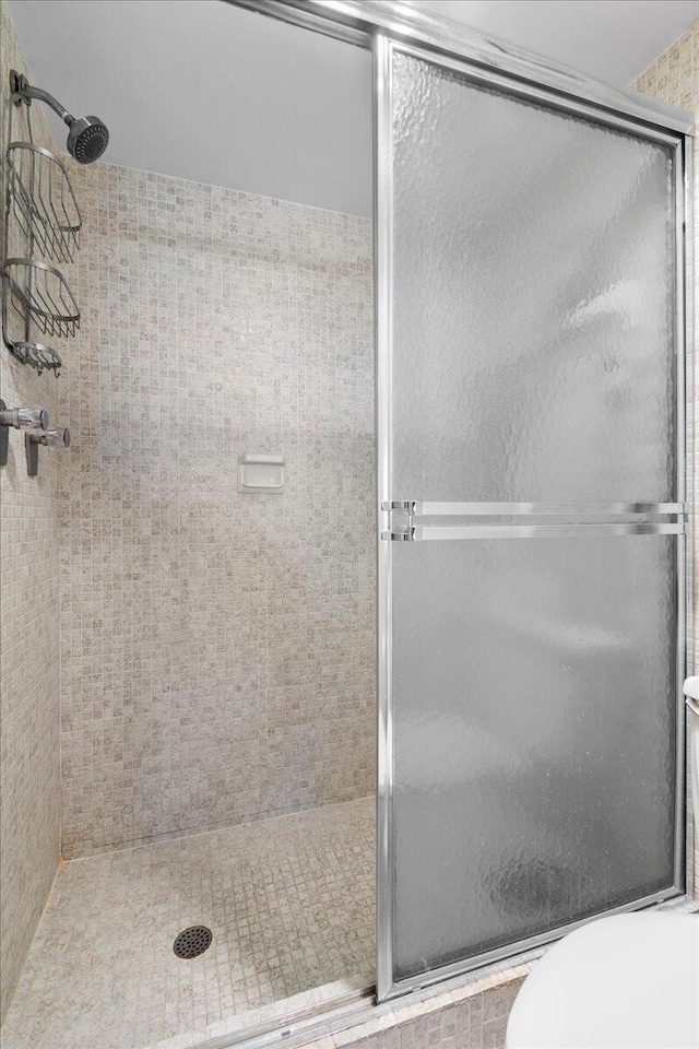 bathroom with a shower with shower door and toilet