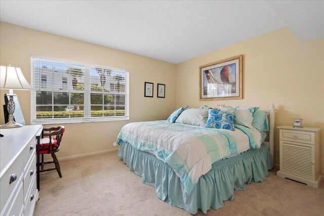 bedroom featuring light colored carpet and a textured ceiling