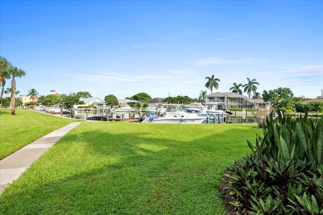 view of home's community with a lawn, a water view, and a boat dock