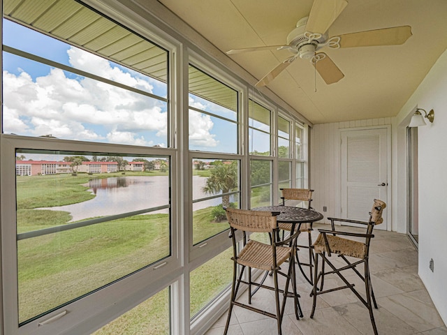 sunroom featuring a water view and ceiling fan