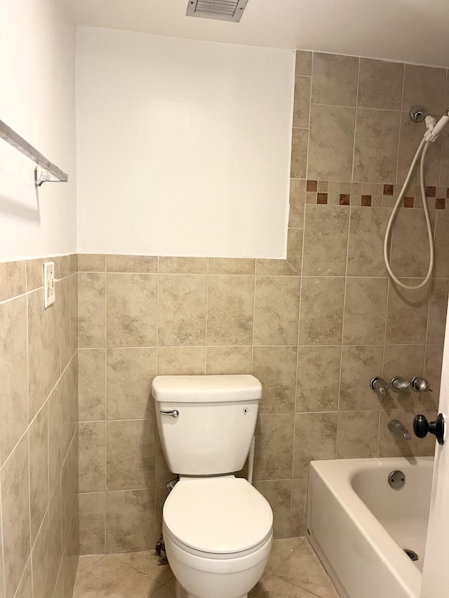 bathroom with tiled shower / bath, tile walls, tile patterned flooring, and toilet