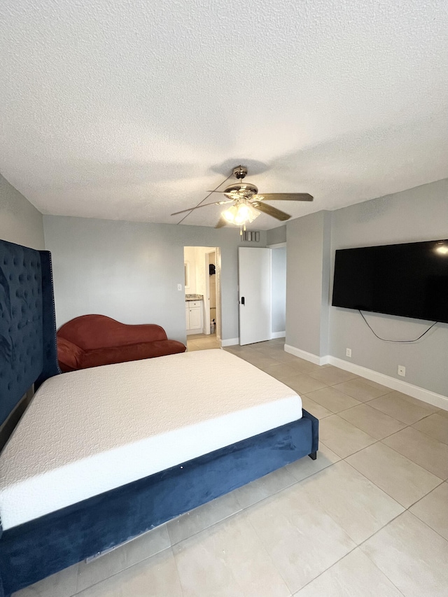 bedroom featuring ceiling fan, a textured ceiling, ensuite bathroom, and tile patterned flooring