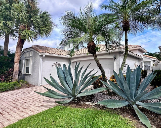 view of side of home featuring a tiled roof, a garage, and stucco siding