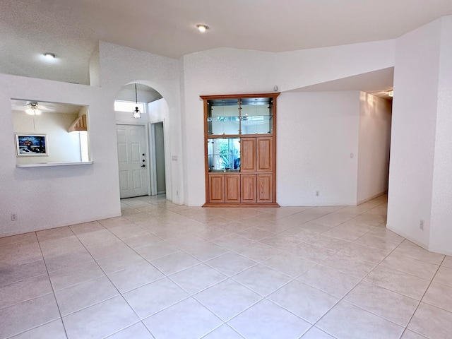 spare room featuring light tile patterned floors, lofted ceiling, and ceiling fan