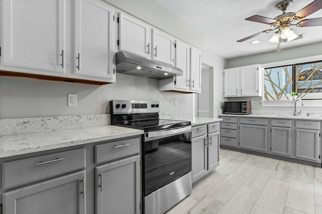 kitchen with stainless steel electric stove, sink, ceiling fan, gray cabinets, and light stone countertops