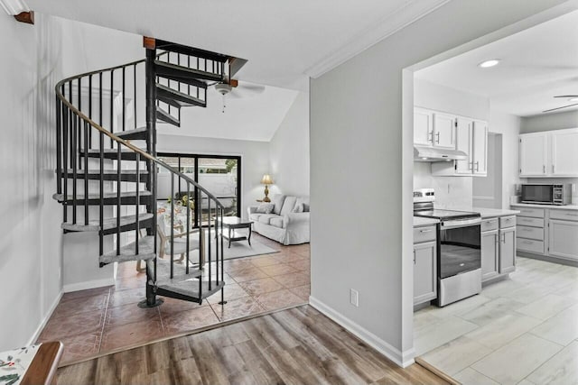 staircase with hardwood / wood-style flooring, ceiling fan, and lofted ceiling