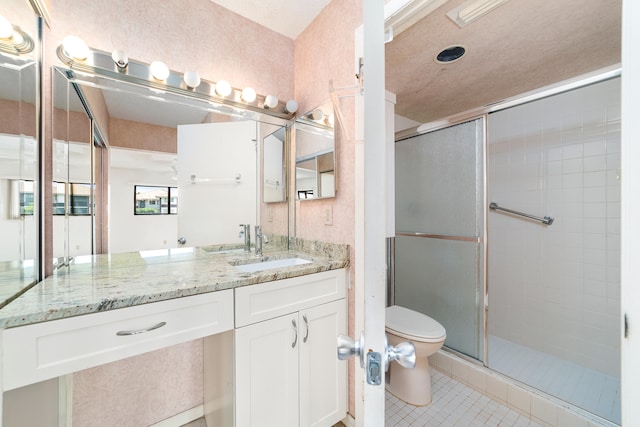 bathroom with tile patterned floors, a shower with door, vanity, and toilet