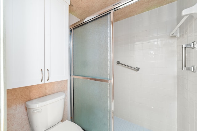 bathroom with a shower with shower door and toilet