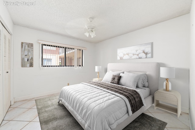 tiled bedroom with ceiling fan, a textured ceiling, and a closet